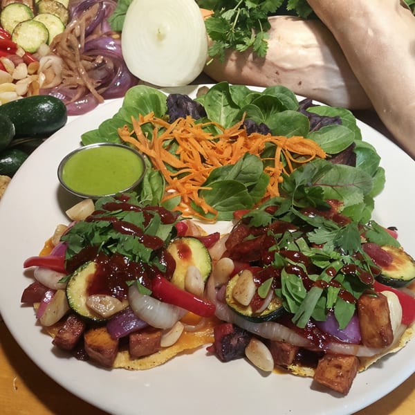 Fudenjuce's healthy tostadas with vegetables, tofu, and green sauce, surrounded by fresh produce.